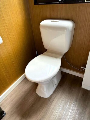 A white toilet in a bathroom with wooden walls and flooring. - Sunshine Coast Glamping in a Tiny House for a Nature Escape in Queensland (Palmwoods)