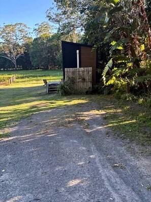 Un sendero de grava que conduce a una pequeña construcción con valla de madera y un banco.
