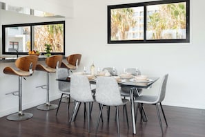 Un espace repas moderne avec une table rectangulaire, six chaises et un tabouret de bar.