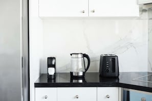 En bordplade med kaffemaskine, elkedel og brødrister.