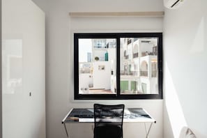 A room with a desk, a chair, and a window overlooking a building with balconies. - Beautiful 2BR Sea View Apt with Dedicated Office (Agios Tychonas)