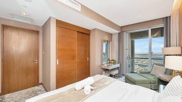 Une chambre d’hôtel comprenant un lit, un bureau, une chaise, une grande fenêtre donnant sur la ville et une porte coulissante.