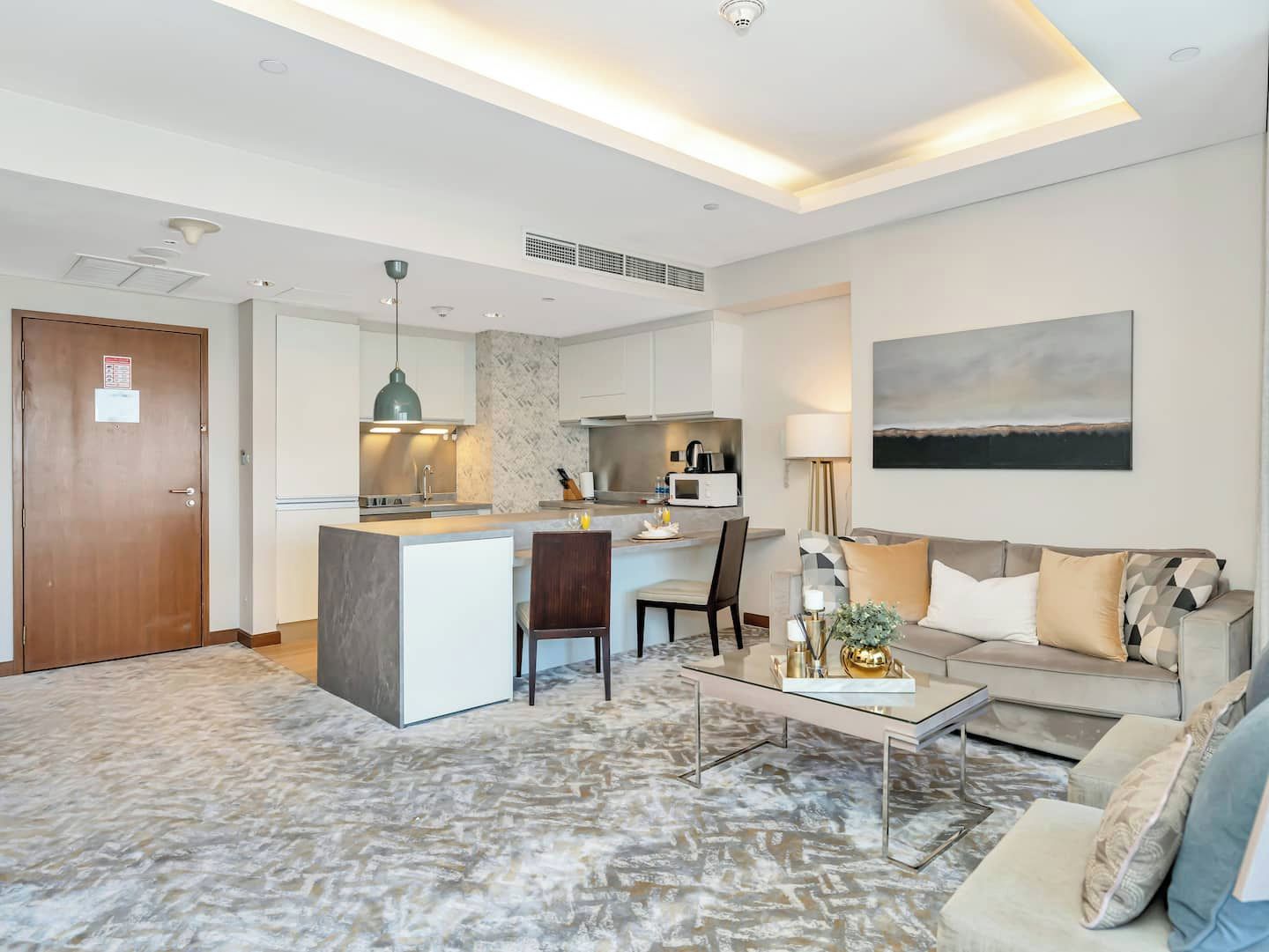 A modern living room with a sofa, coffee table, and a kitchen area with a dining table.