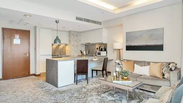 A modern living room with a sofa, coffee table, and a kitchen area with a dining table.