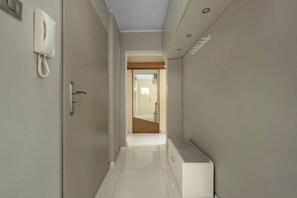 A narrow hallway with a telephone on the left, a door with a handle, and a bench on the right. - Wroclaw | 29 Budziszyńska | Bright Apartment | Coffee machine (Wrocław)
