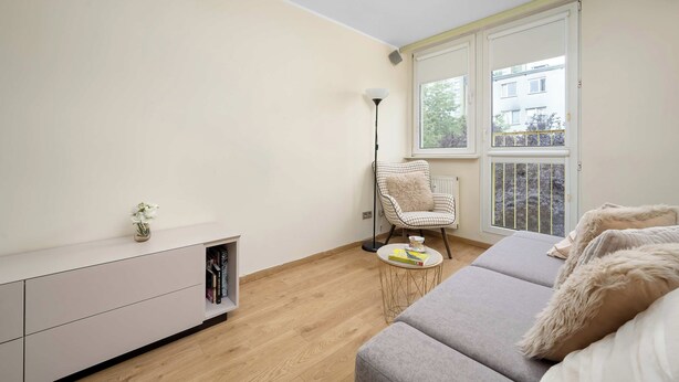 En moderne stue med sofa, stol, lille bord og bogreol.