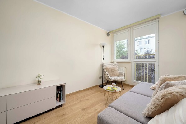 A modern living room with a sofa, a chair, a small table, and a bookshelf. - Wroclaw | 29 Budziszyńska | Bright Apartment | Coffee machine (Wrocław)