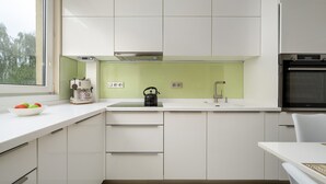 Et moderne køkken med hvide skabe, en grøn backsplash, en elkedel og en kaffemaskine på bordet.