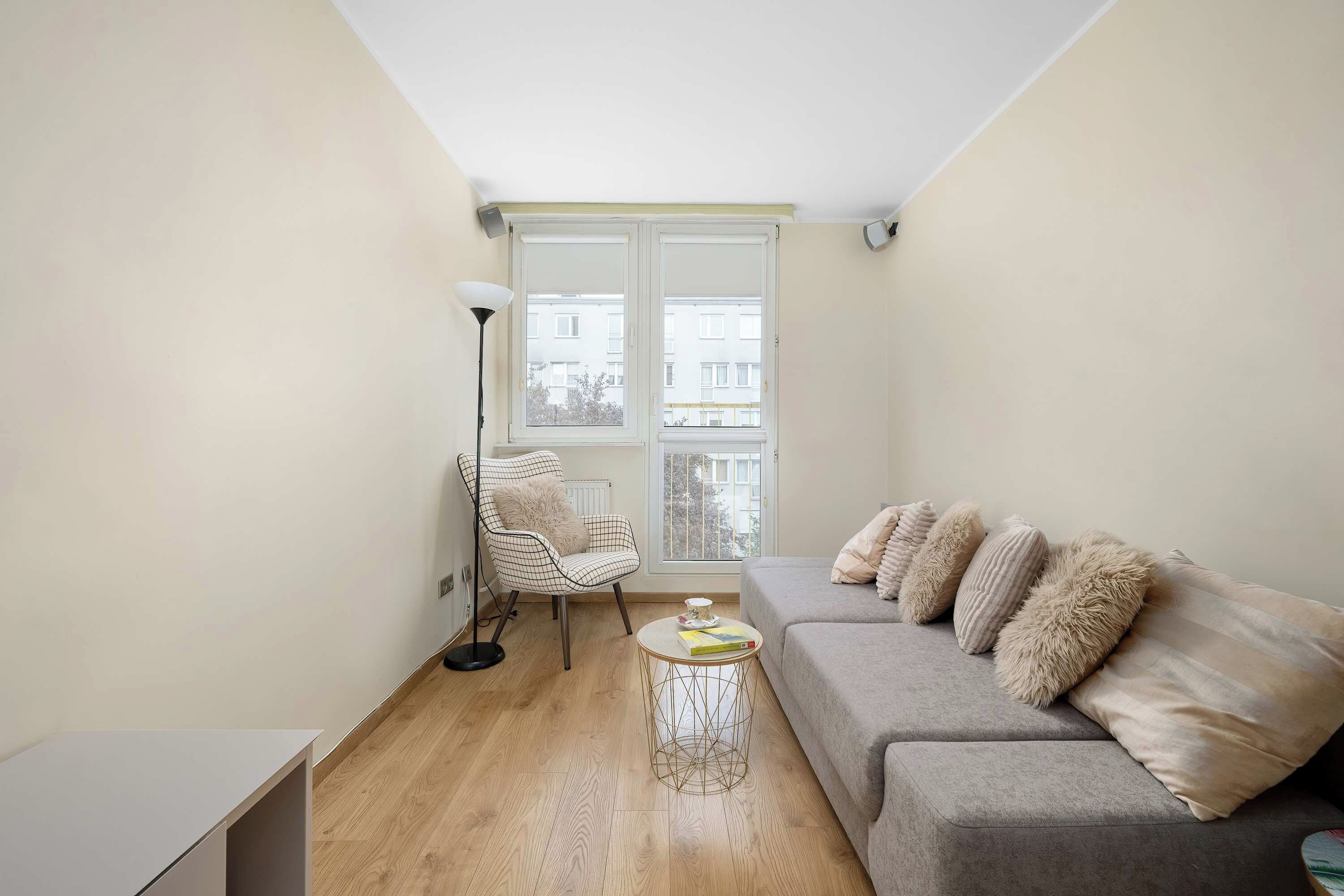 A living room with a sofa, a chair, a floor lamp, and a table.
