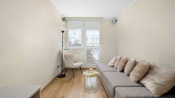 A living room with a sofa, a chair, a floor lamp, and a table.