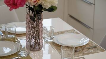 Una mesa de comedor servida con platos, cubiertos y un florero con flores.