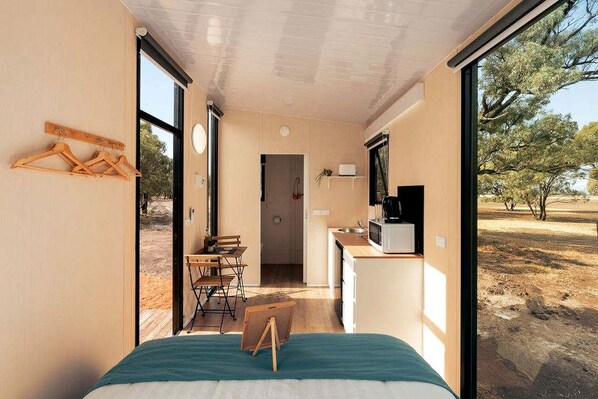 A compact room with a bed, a desk, and a kitchenette.