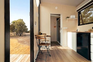 A compact kitchen with a dining area, a built-in dishwasher, and a view of a dry landscape.