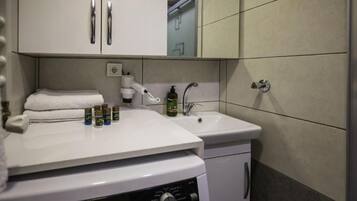 A hotel bathroom with a washing machine, a sink, and toiletries.