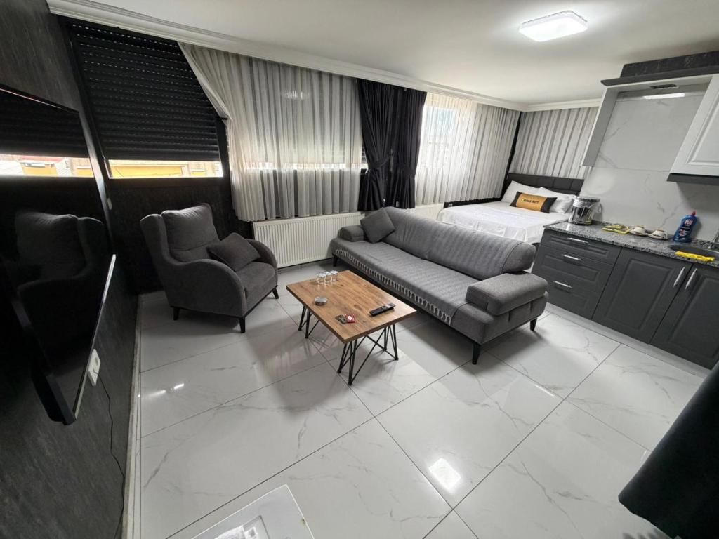 A modern hotel room with a sofa, a small table, a bed, and a kitchenette.