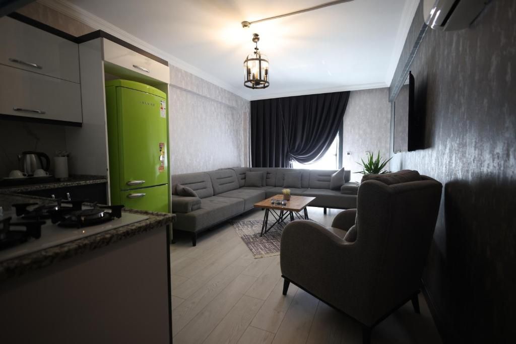 A modern living room with a sectional sofa, a coffee table, and a dining area with a green refrigerator.