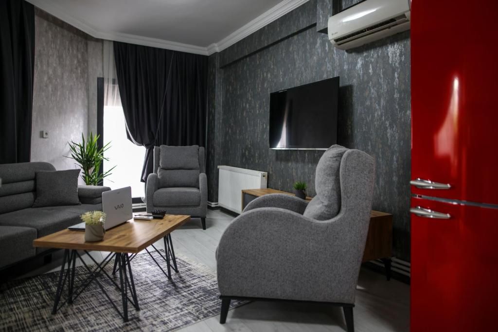 Una sala de estar moderna con un sofá gris, un sillón gris, una mesa de centro de madera y un aparador rojo.