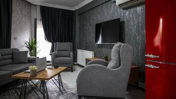 A modern living room with a grey sofa, a grey armchair, a wooden coffee table, and a red cabinet.