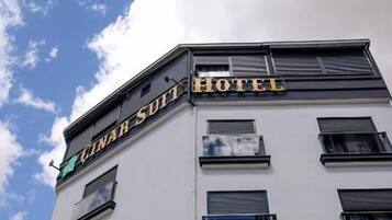 Edifício de hotel com uma placa que diz 'CINAR SUIT HOTEL' e uma bandeira com uma lua crescente e uma estrela.