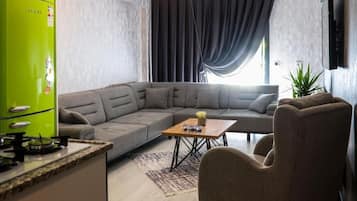 A modern living room with a sectional sofa, a coffee table, and a green refrigerator.