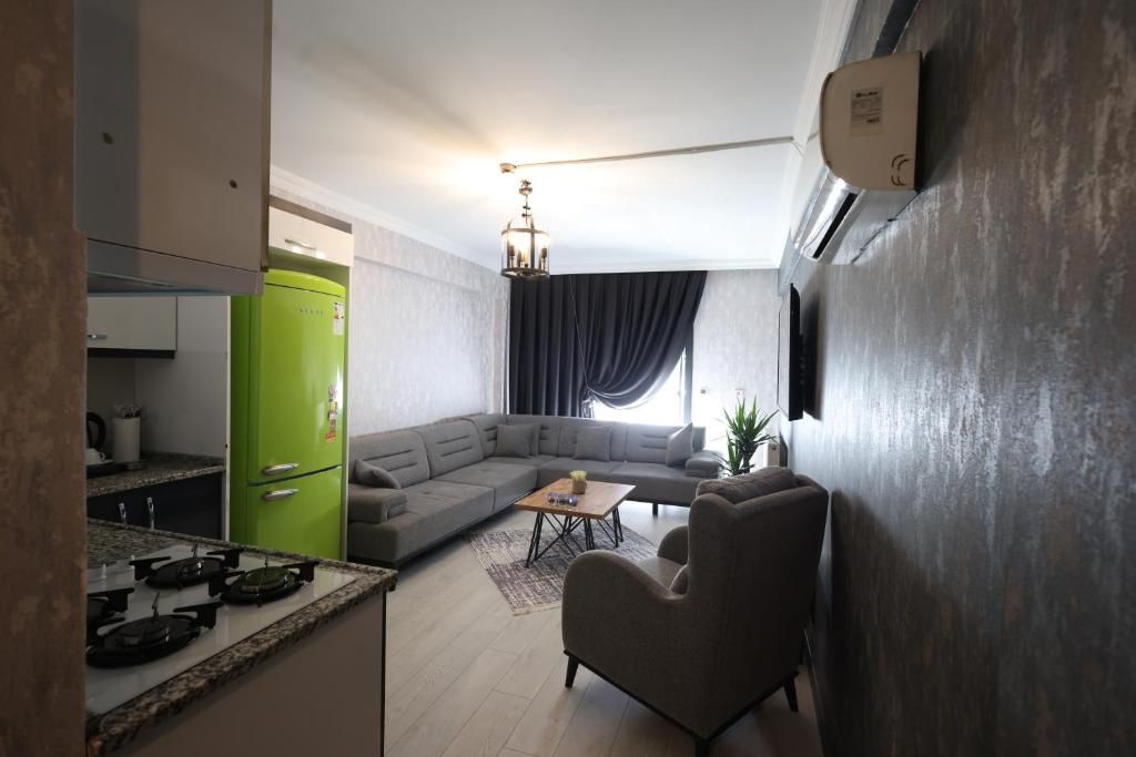 A modern kitchen with a green refrigerator, a dining area with a sofa and a coffee table, and a living room with a large sectional sofa.