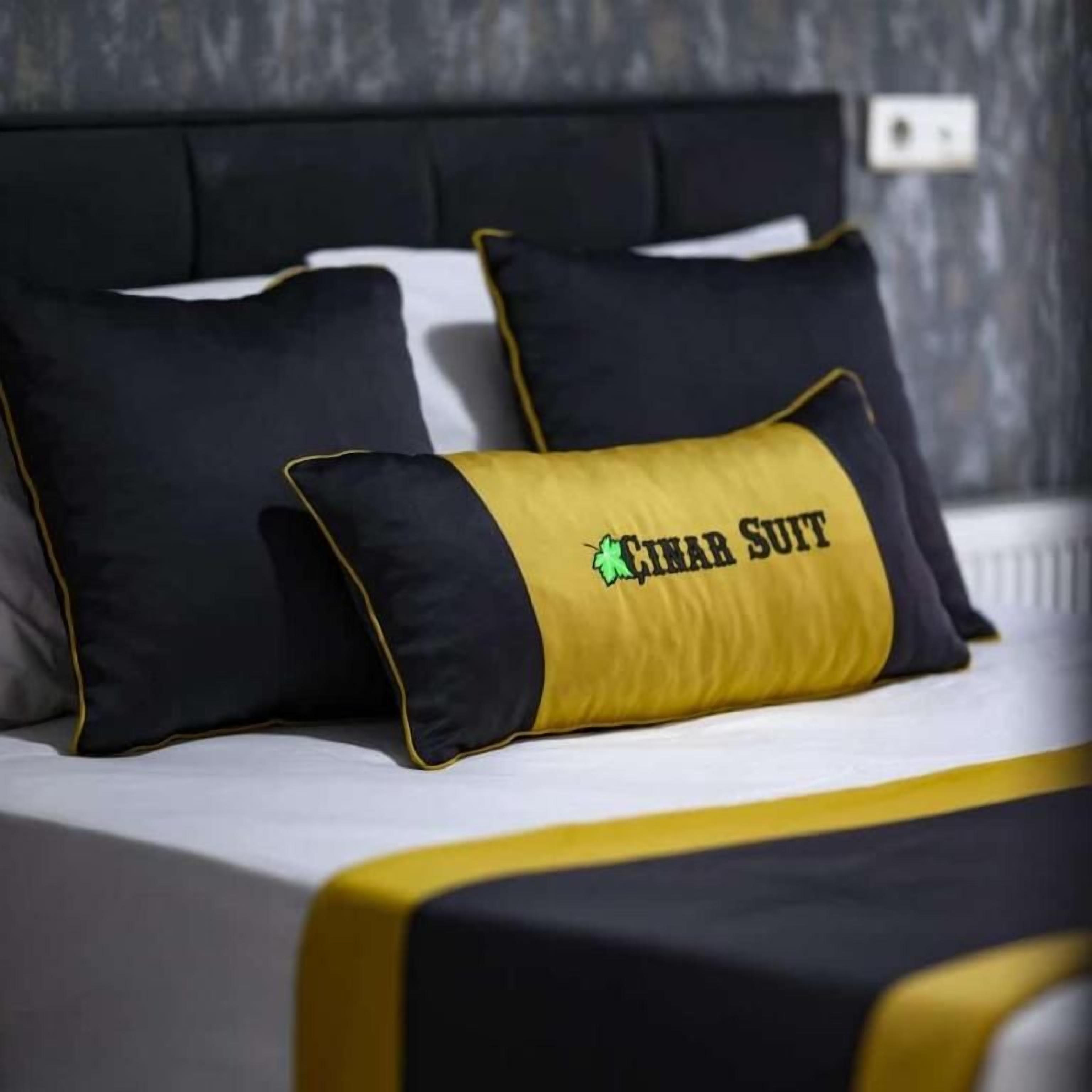 A bed with black and yellow bedding, including pillows with 'HINAR SUIT' text.