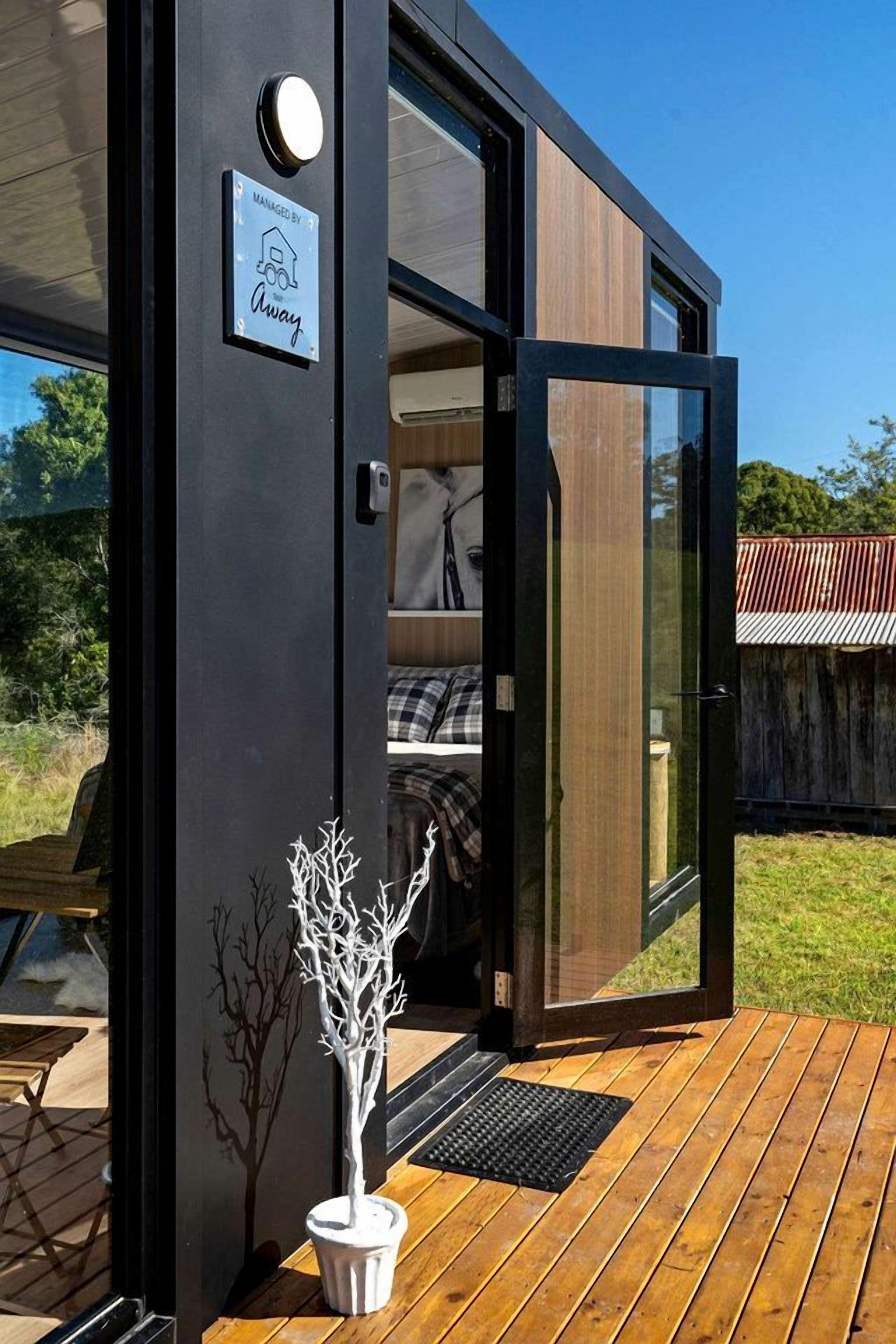A modern building with a glass door leading to a bedroom with a bed and a white potted plant.