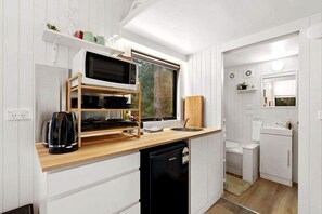 Eine kleine Küche mit Mikrowelle, Wasserkocher und Holzregalen.