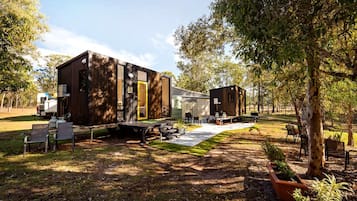 Ein modernes Wohnmobil-ähnliches Gebäude mit einer überdachten Außenfläche, einem Picknicktisch und einer kleinen Terrasse.