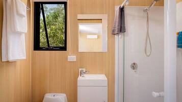 A compact bathroom with a window, a shower, and a toilet.
