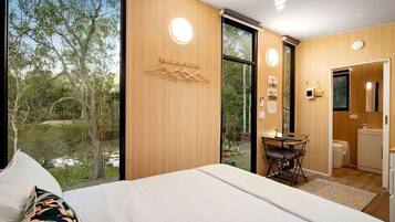Un dormitorio con una cama grande, un escritorio y vistas a un paisaje natural.