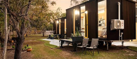 Une maison mobile moderne et compacte, dotée de grandes fenêtres, d’un coin repas et d’une terrasse.