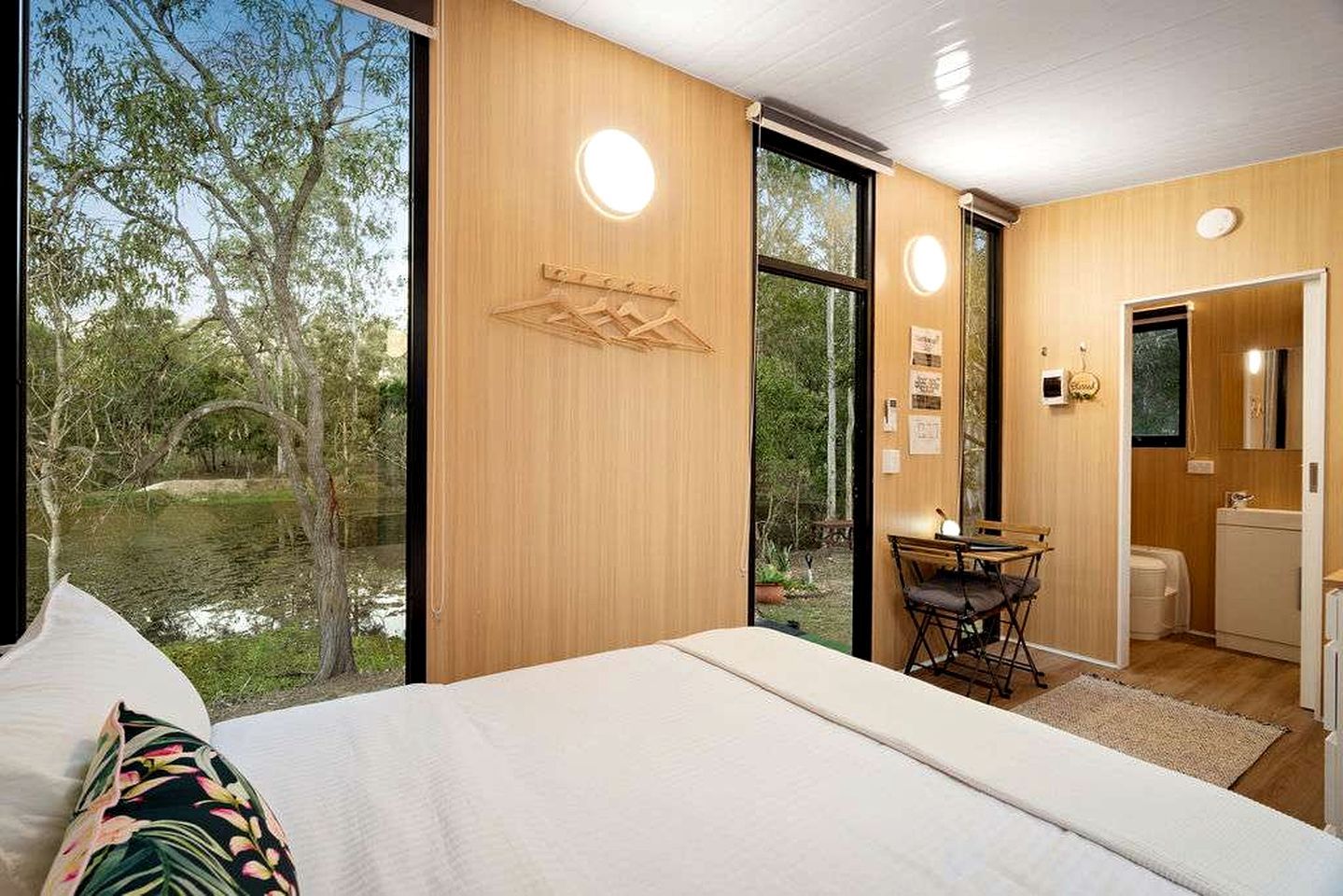 A bedroom with a large bed, a desk, and a view of a natural landscape.