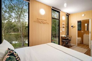 Een slaapkamer met een groot bed, een bureau en uitzicht op een natuurlandschap.