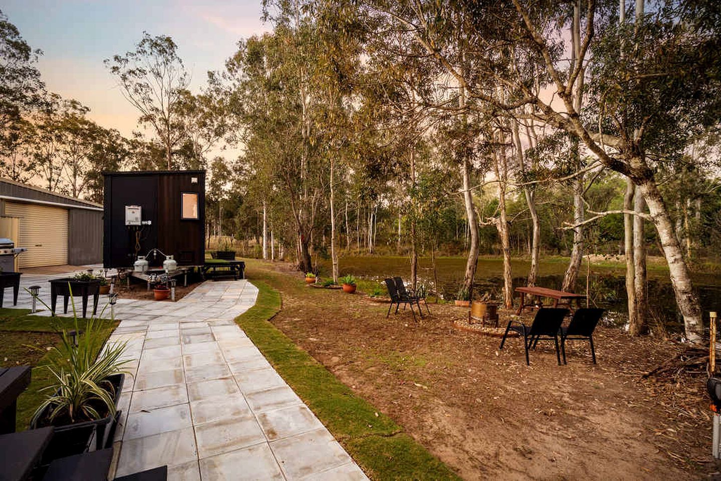Un jardin avec une terrasse, un coin salon extérieur et un petit abri de jardin.
