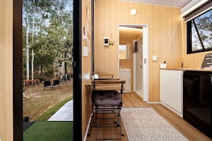 A compact living space with a kitchenette, a dining area, and a view of the outdoors.