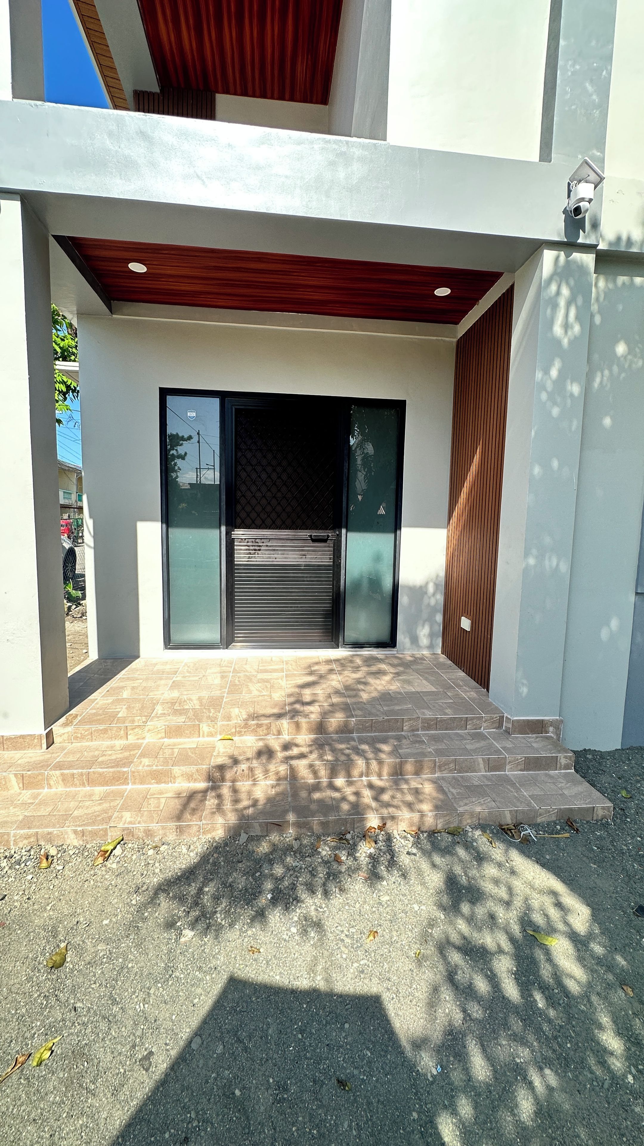 A modern building entrance with a closed garage door, a set of steps leading up to the entrance, and a security camera mounted on the wall.