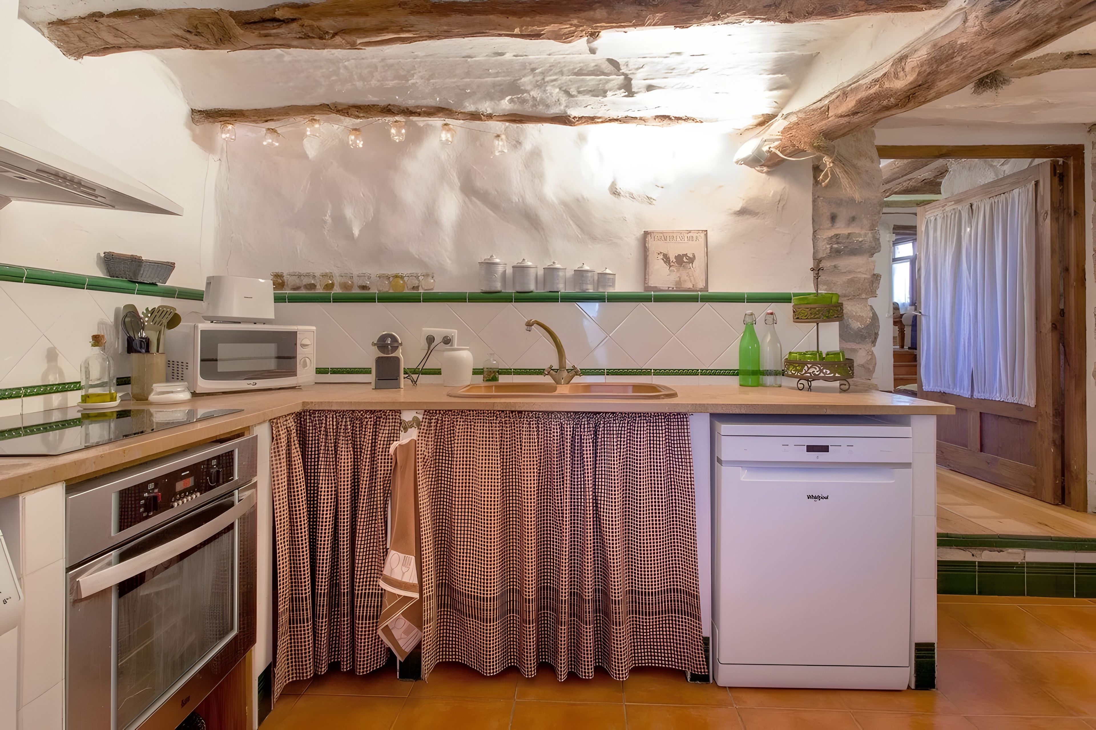 Cocina compacta con lavavajillas integrado, microondas y fregadero.