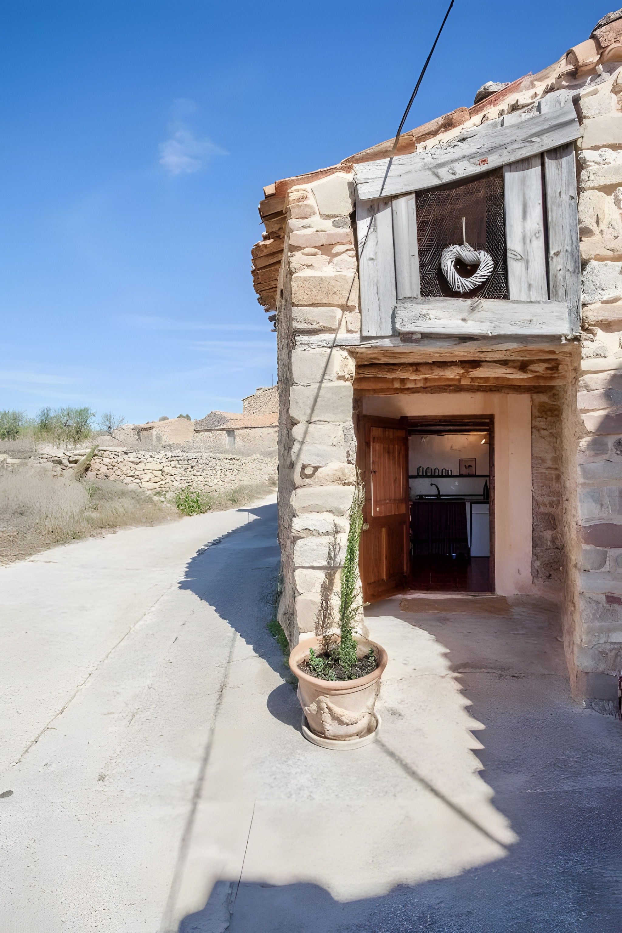 A rustic stone building with a wooden door and a small potted plant.