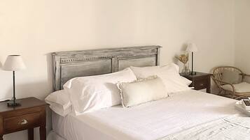 Una camera da letto con un letto, comodini, una sedia e una lampada a sospensione.