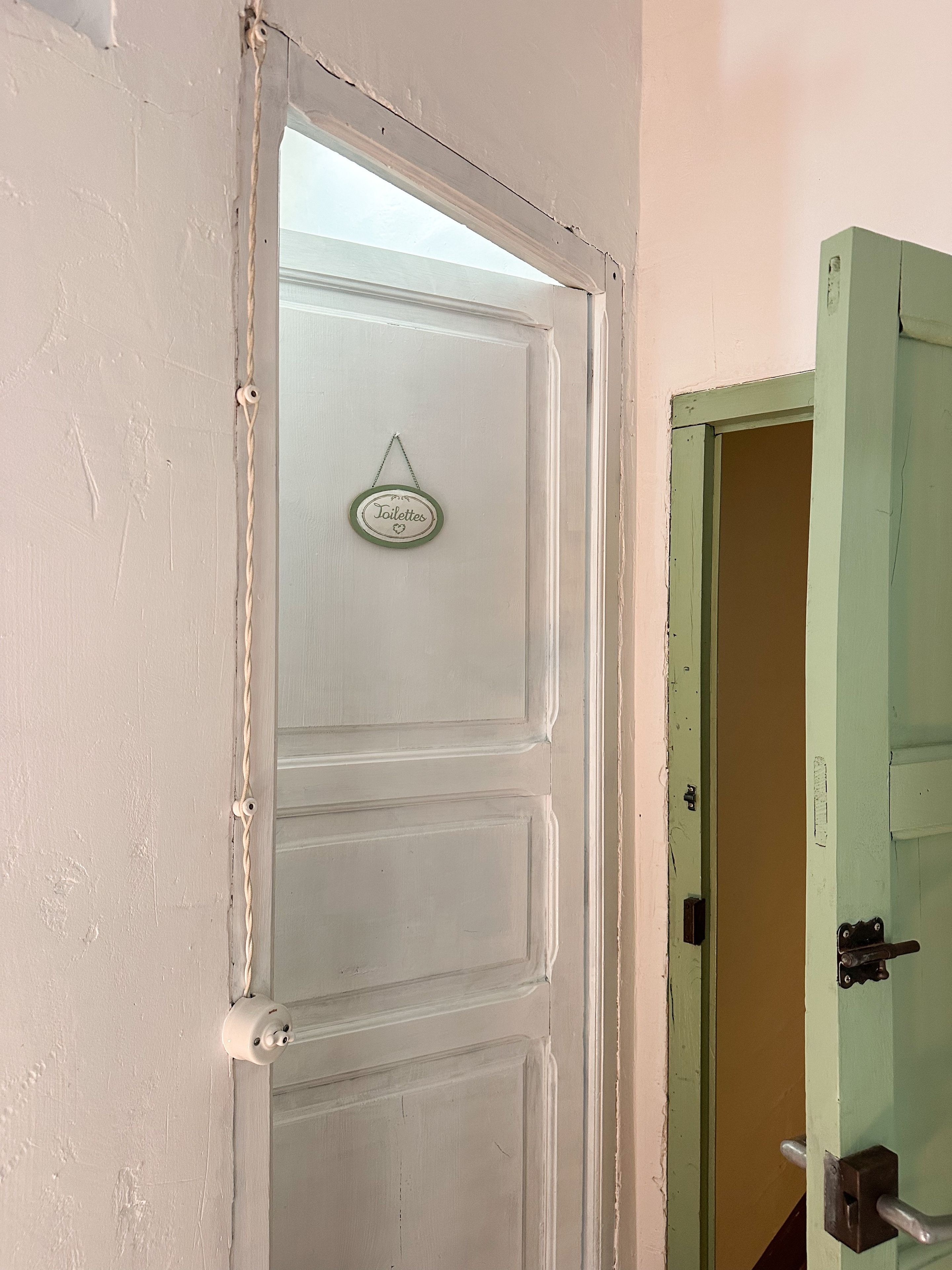 Une porte entrouverte, avec une pancarte indiquant « Toilettes » accrochée au mur.