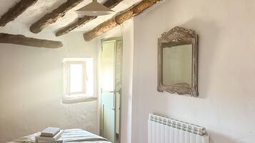 Een slaapkamer met een bed, een radiator, een spiegel en een raam.