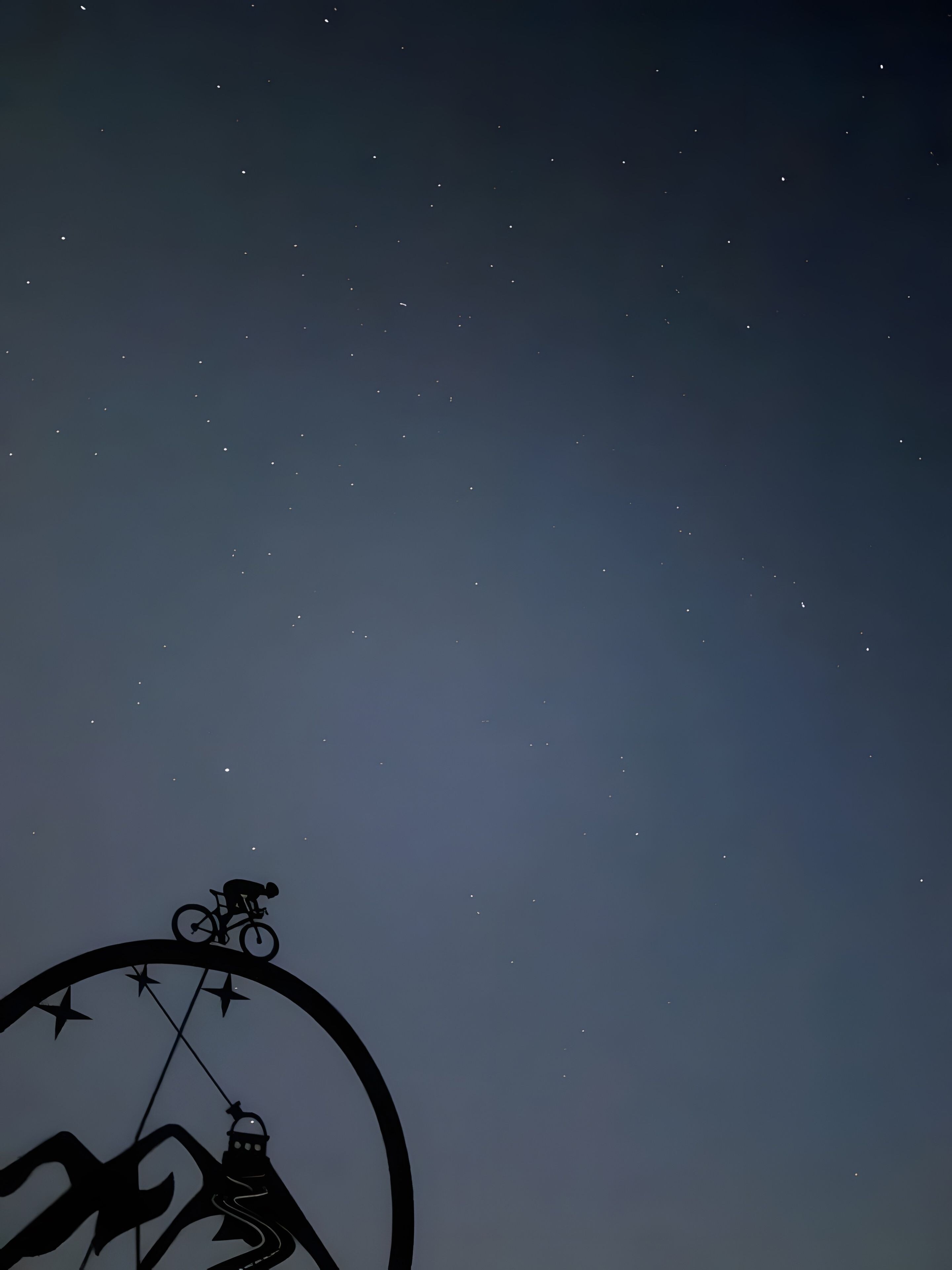 Un ciel étoilé et la silhouette d’une personne à vélo.