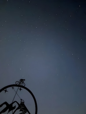 Sternenklarer Nachthimmel mit der Silhouette einer Person auf einem Fahrrad.
