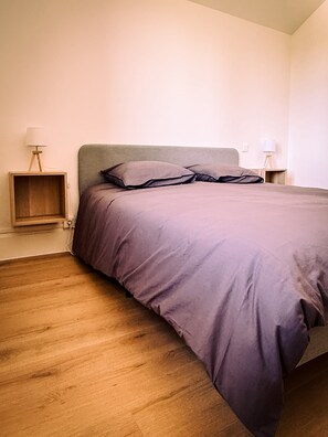 A bedroom with a bed, wooden flooring, and bedside lamps. - Family-Friendly Village House - LA PERLA (Éloyes)