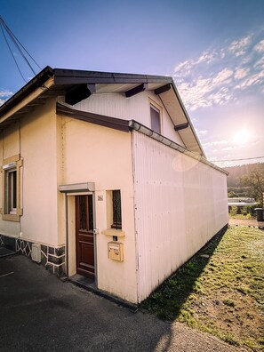 A single-story building with a sloped roof, a front door, and a small porch area. - Family-Friendly Village House - LA PERLA (Éloyes)