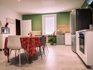 Une cuisine moderne avec un coin repas, équipée d’un four à micro-ondes, d’un réfrigérateur et d’un plan de travail en bois.