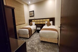 Quarto de hotel com duas camas, cabeceira de madeira, quadro emoldurado na parede e piso coberto por carpete.