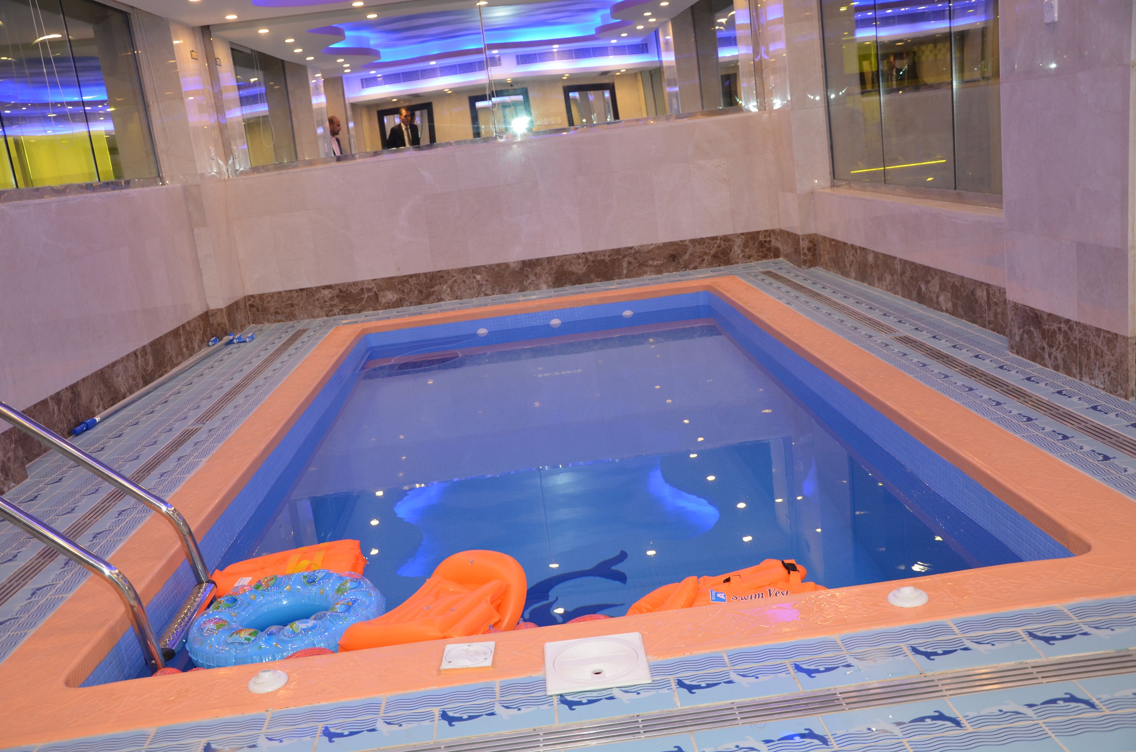 A swimming pool with a blue and orange color scheme, surrounded by a tiled deck.