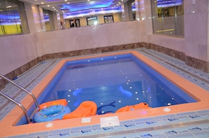 A swimming pool with a blue and orange color scheme, surrounded by a tiled deck.